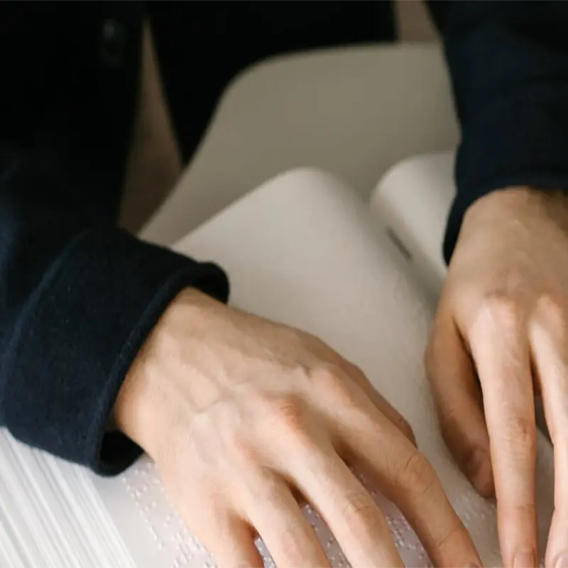 Persona invidente leyendo un libro braille como ejemplo de vocación para las oposiciones de Tests y Simulacros de EEE